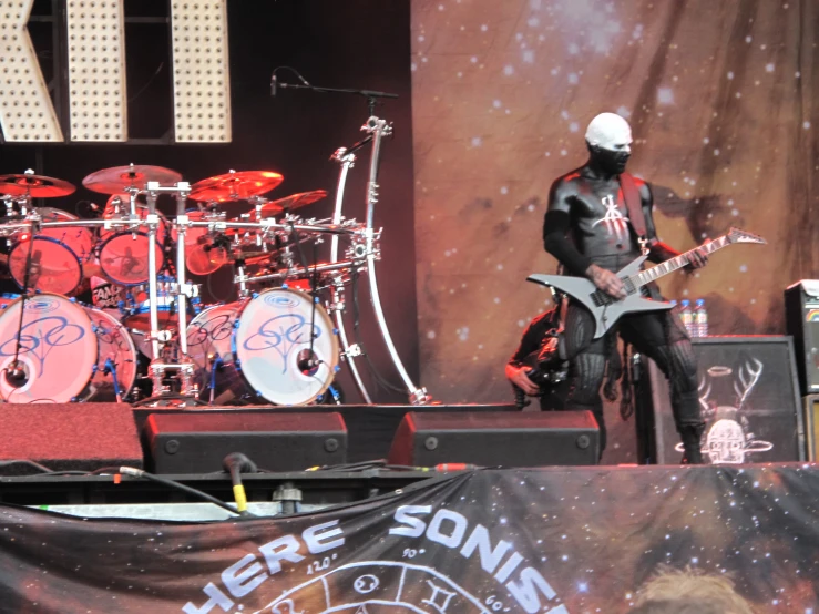 a person in white mask playing guitar on stage