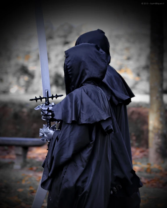 a person in dark clothing holding a sword