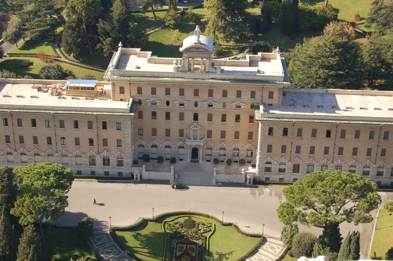 an aerial view of a building with a circular courtyard and gardens in front of it