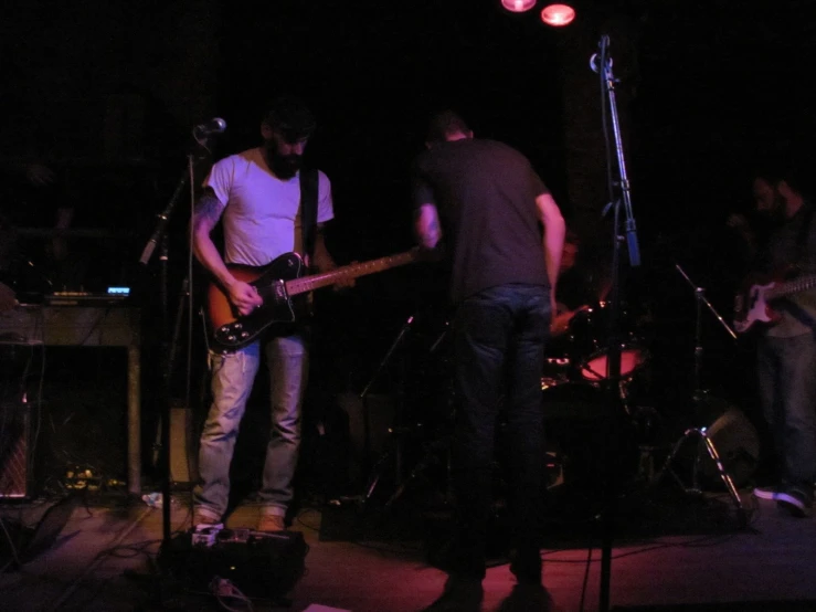 two young men playing instruments in a darkened room