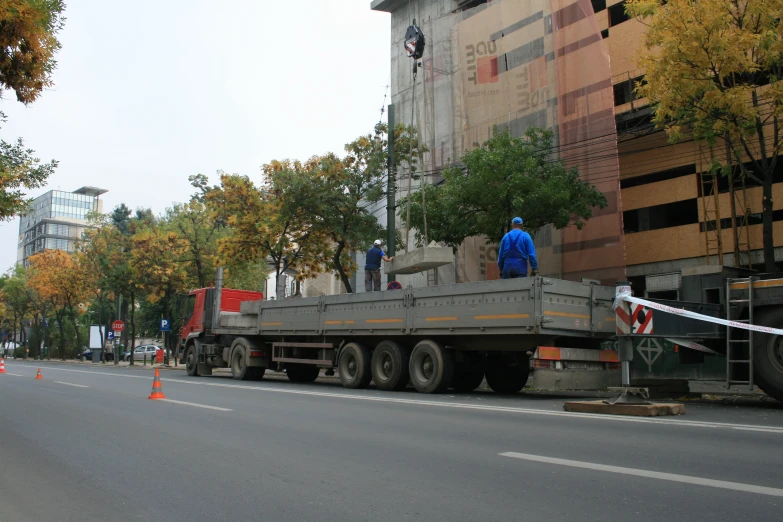 a large flatbed truck is stopped down a busy street