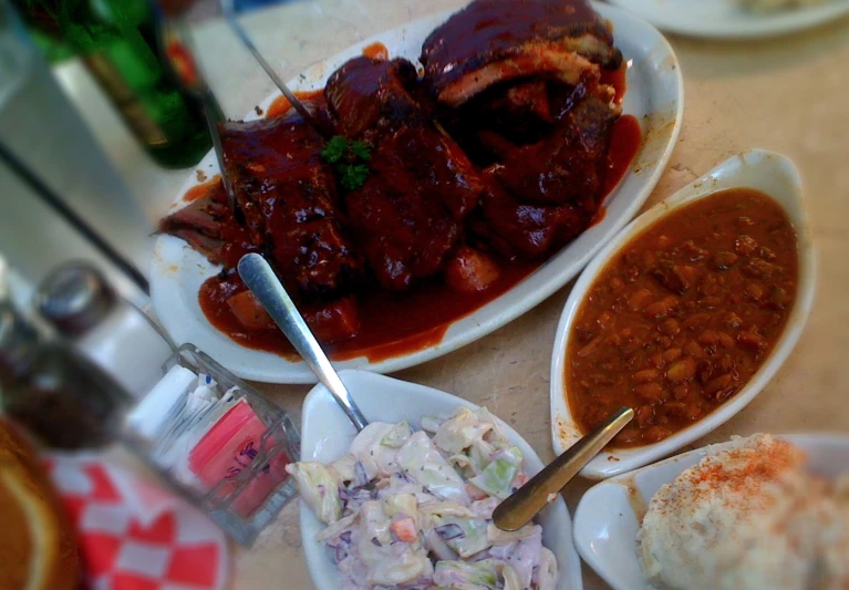 a few plates with food that include ribs, beans and rice