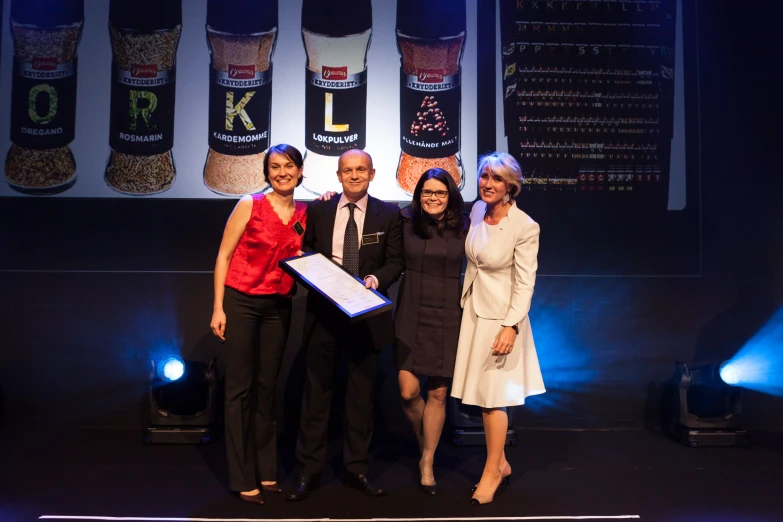 three woman and a man standing on stage in front of the stage