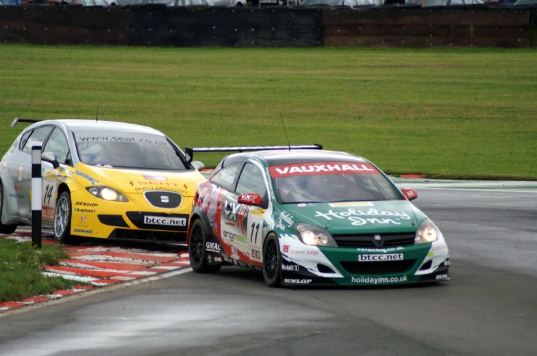 two cars going around a curve, one is yellow and the other is green