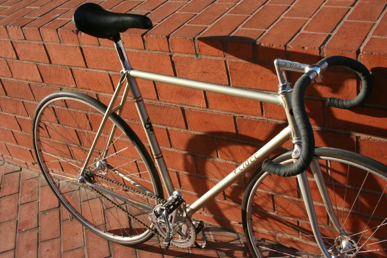 a shiny silver bicycle sits next to a brick wall