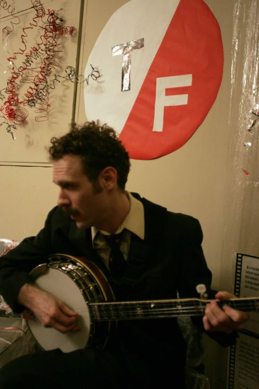 a man playing the guitar by the frisbee hanging on a wall