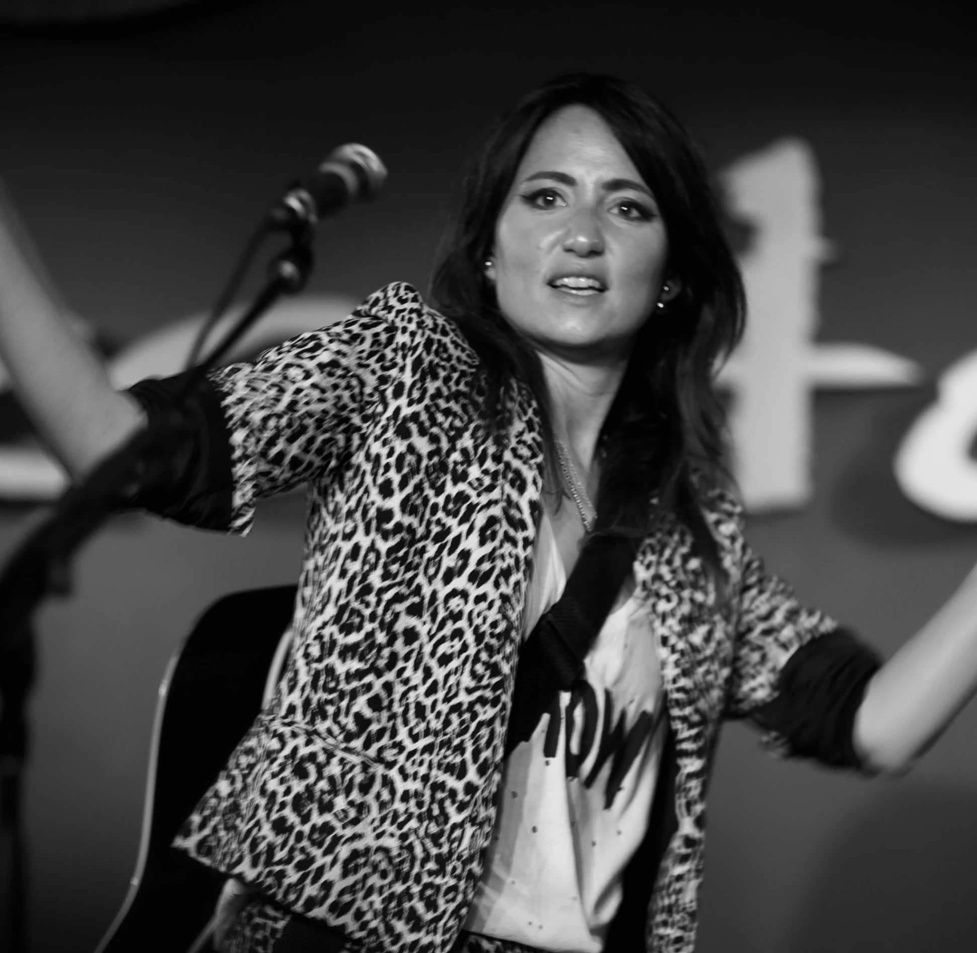 a lady standing behind a microphone with one hand on her hip