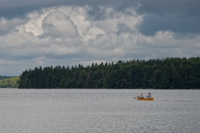 a boat is on a large lake and there is some clouds in the sky