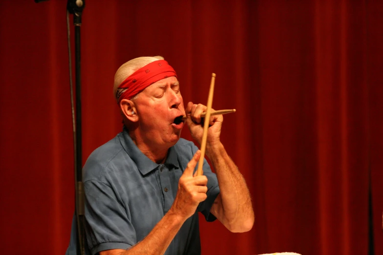 a man with a bandana on and holding sticks