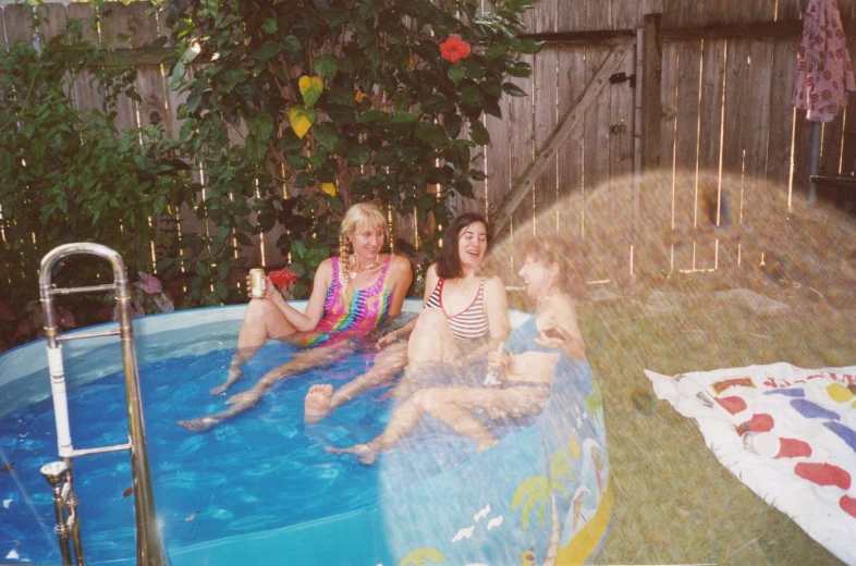 three women sitting in a large pool with two children