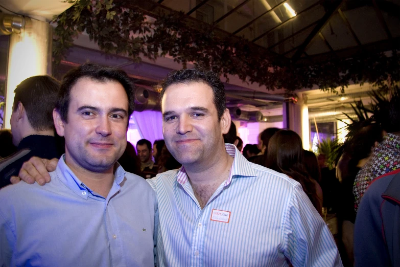 two men standing together in a crowded restaurant