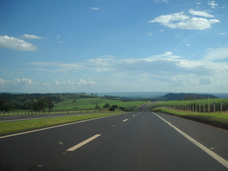 a rural roadway with tall grass and blue skies