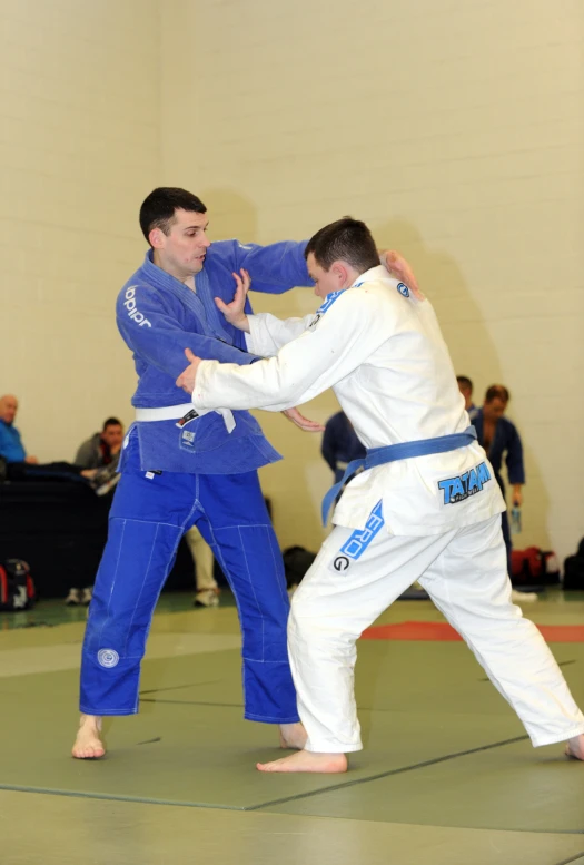 two men with black belt and blue pants compete in martial