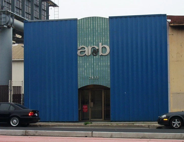 two cars parked outside of a building with a blue facade