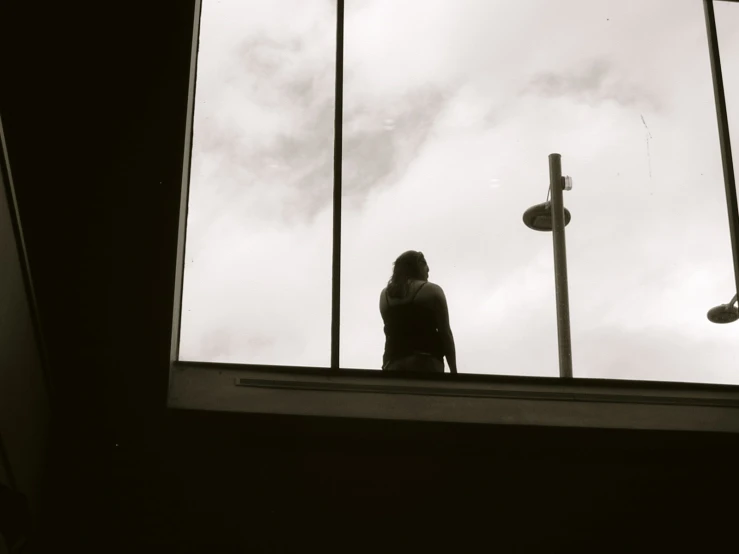 a woman sits in a window looking out of the window