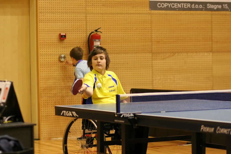 a young man playing table tennis in an indoor room