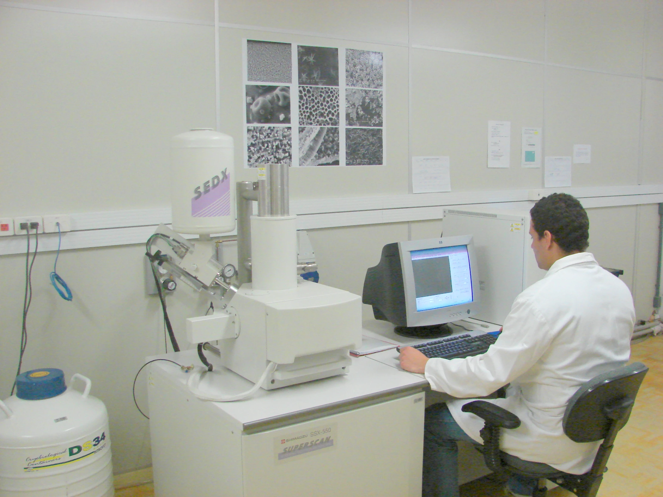 a man sits at a computer in front of a microscope