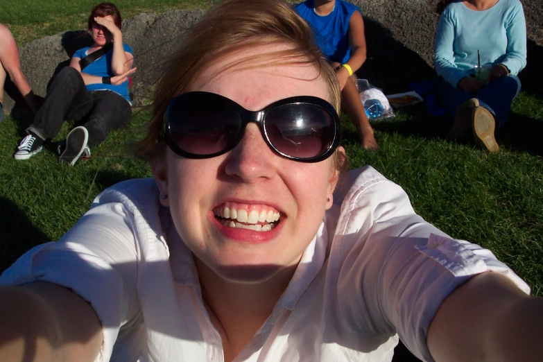 a woman wearing sun glasses looking up while laying on grass