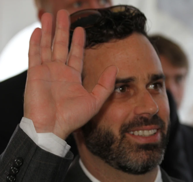 man wearing suit holding up his right hand