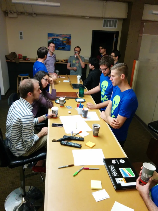 people in a large meeting room are seated around a long table