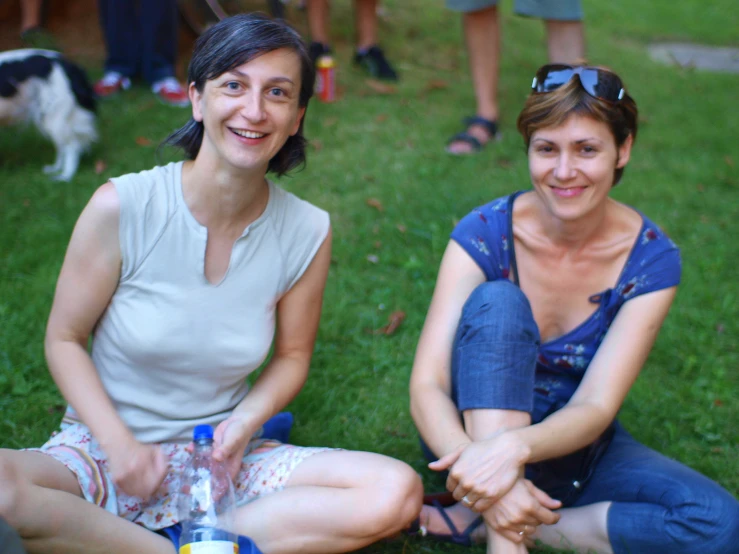 two women with glasses sitting on the grass