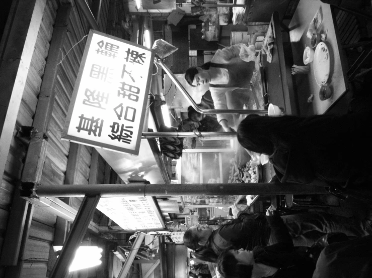 people are eating at a food stand near signs