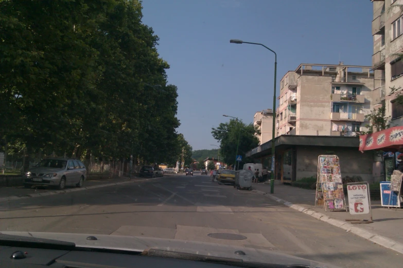 an empty street with signs on the sidewalk and trees