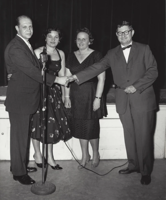 people standing around an award winning microphone and shaking hands