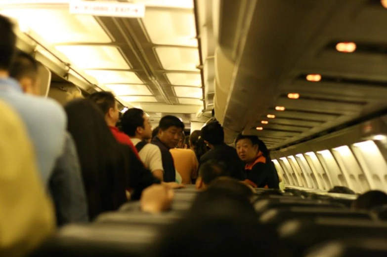 people standing inside an airplane, with a few passengers