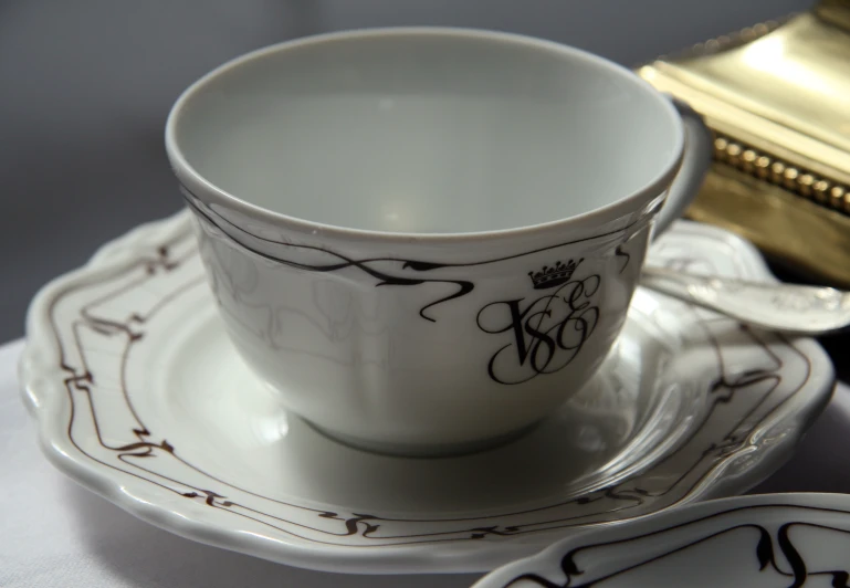 white and black ceramic tea cup with gold decoration