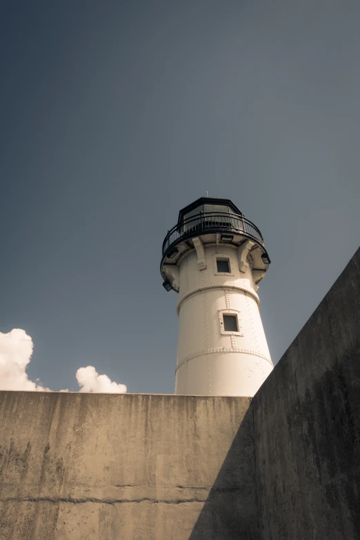 a lighthouse on a concrete structure with clouds in the background