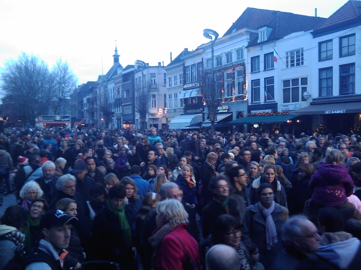 a large crowd of people are gathering around in front of some buildings