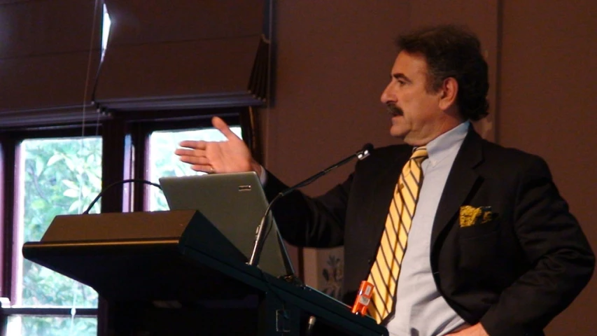 a man in a suit speaks while holding a microphone