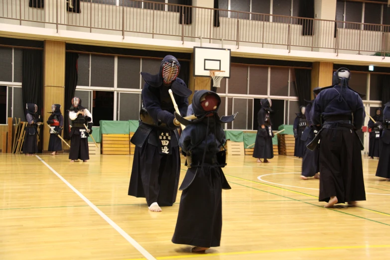 three people wearing black masks and playing a game in a gym