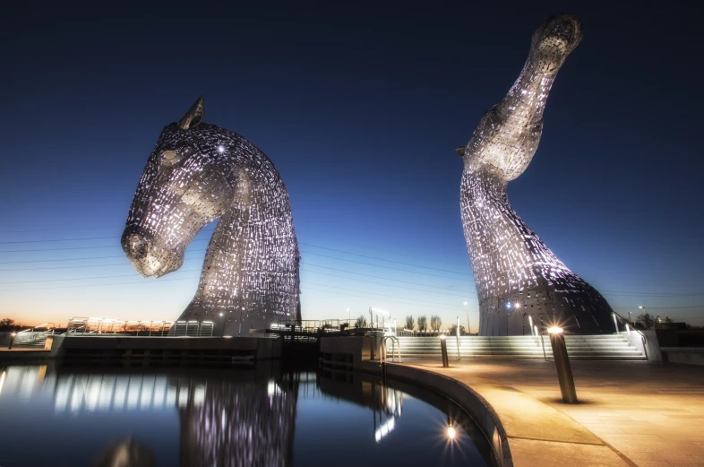 a horse statue is next to water at night