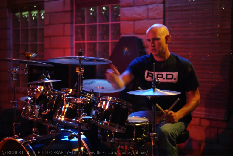 man sitting on stage playing a drum set with his legs crossed