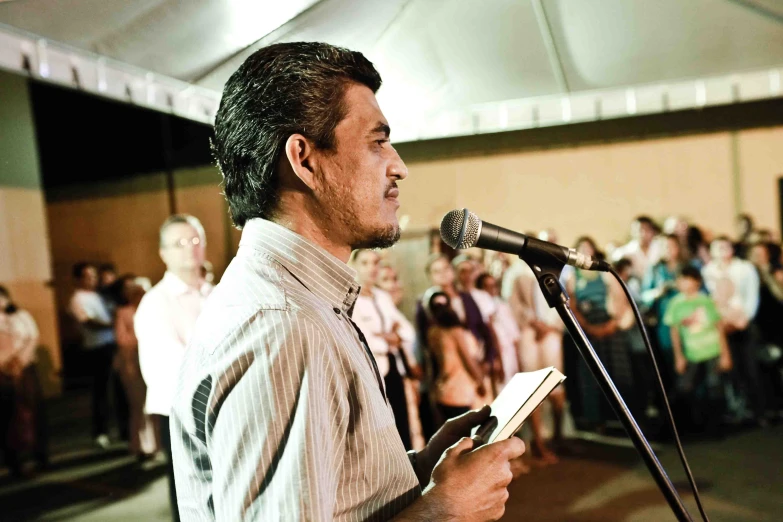 a man standing at a microphone in front of a group of people