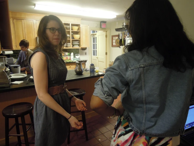 there are two women in the kitchen, one holding her hand out