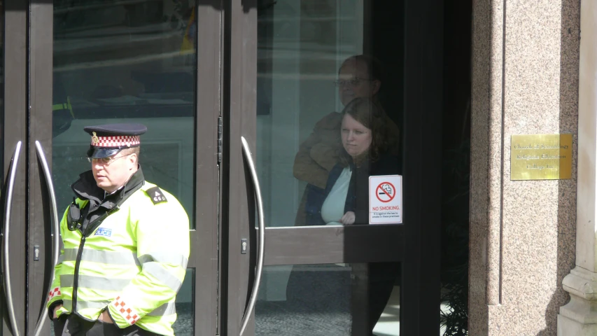 the door to an entrance is open with a police officer in a yellow jacket