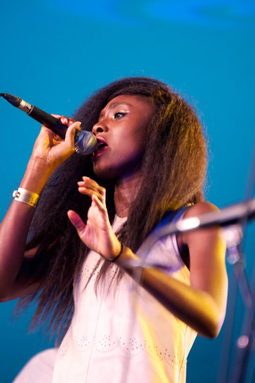 a black woman singing into a microphone on stage