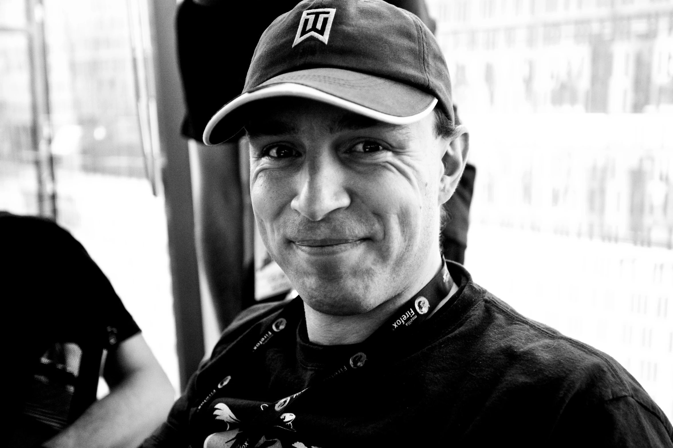 man in baseball cap standing near bus window with smile