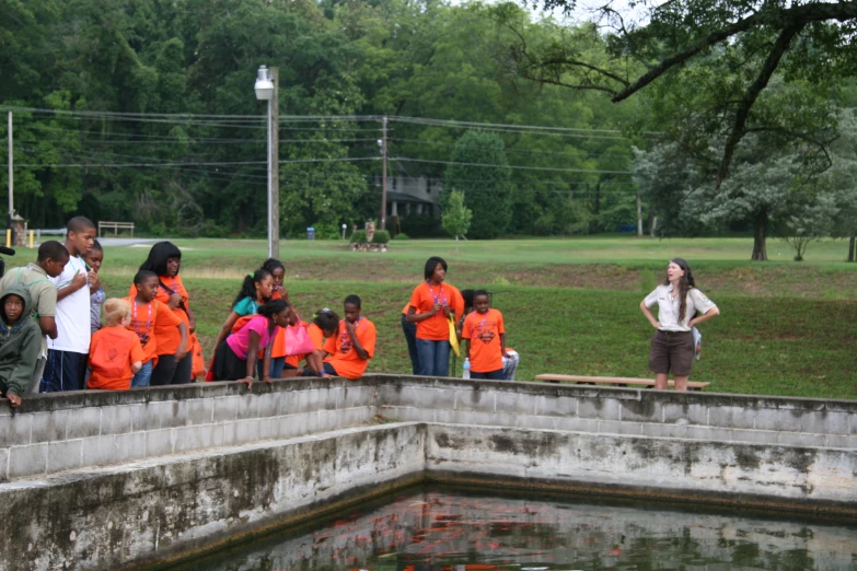 a group of children standing near water and fence