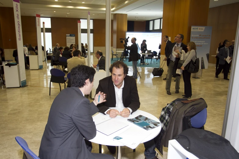 two men at a table discussing soing at an exhibition