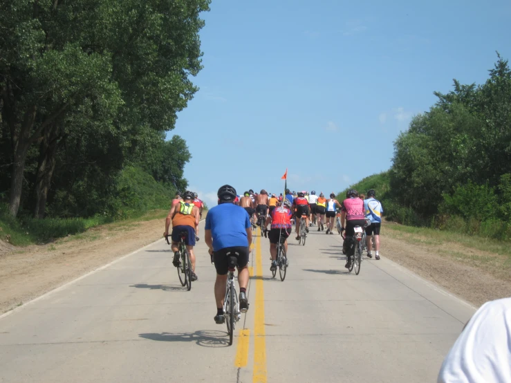 many bicyclists riding down a dirt road