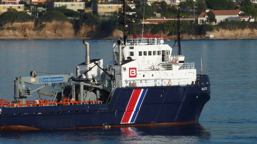 a navy boat sitting next to a shoreline near the city