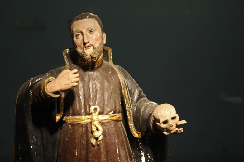 a close up of a small statue of jesus holding a skull