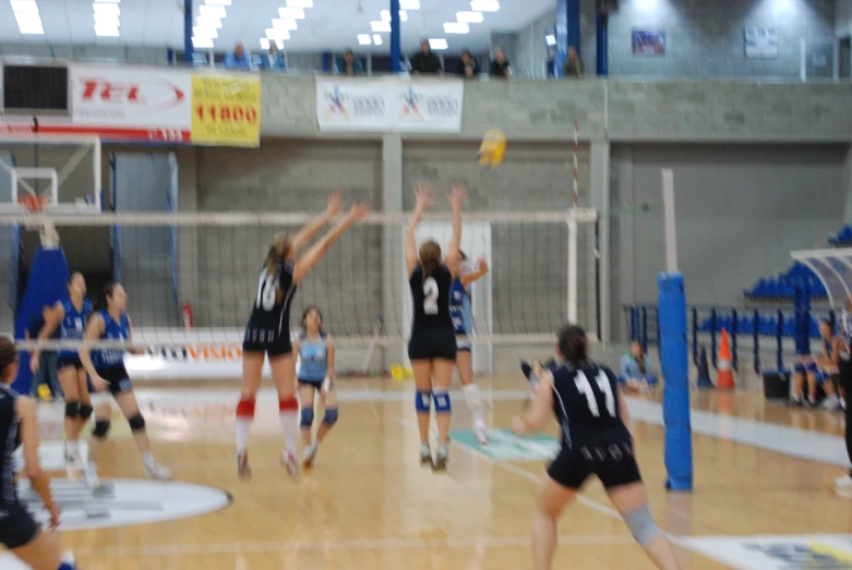 the volleyball team goes to block the ball in the air
