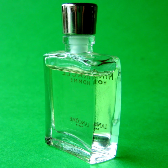 a bottle of cologne on a green background