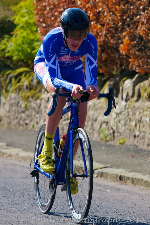 a young man riding a blue bicycle down a road