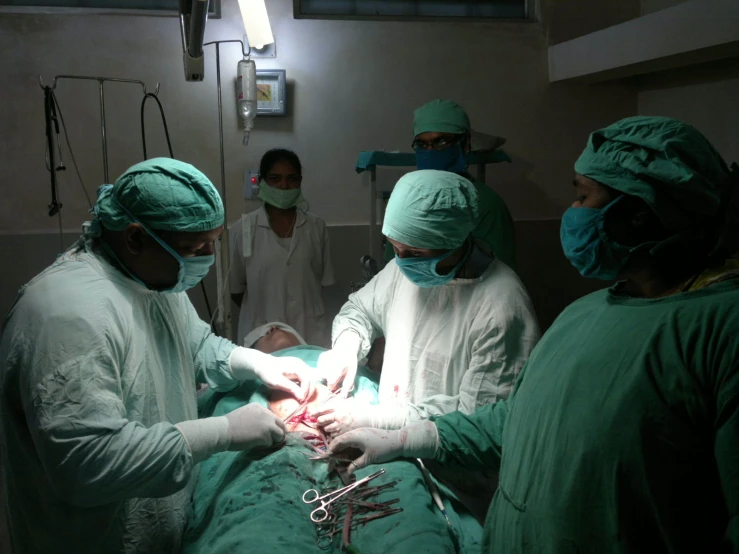 a group of doctors performing  on a person in a hospital bed